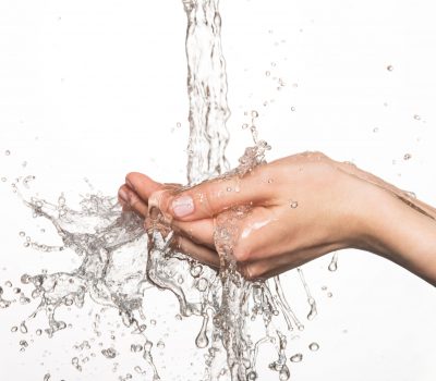 34216000 - closeup female hands under the stream of splashing water - skin care concept
