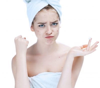 52848915 - scowling girl in shock of her acne with a towel on her head. woman skin care concept, photos of european girl on white background